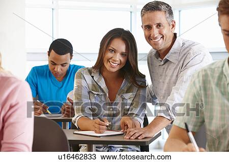 Stock Image - Tutor helping student in class. Fotosearch
