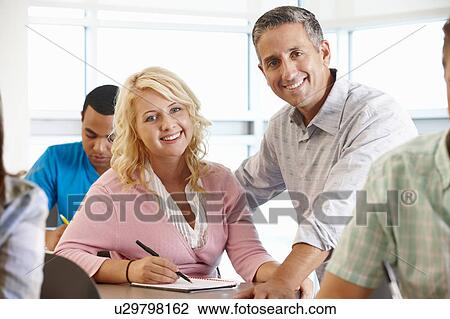 Stock Image - Tutor helping student in class. Fotosearch