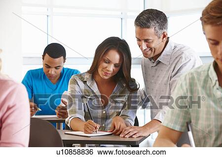 Stock Photograph - Tutor helping student in class. Fotosearch