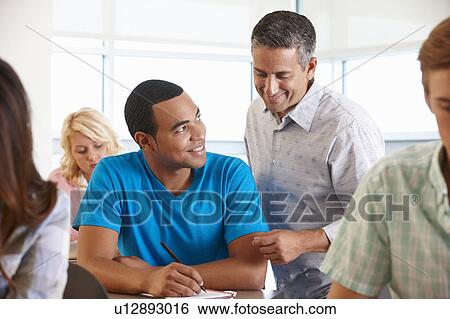 Stock Photograph - Tutor helping student in class. Fotosearch