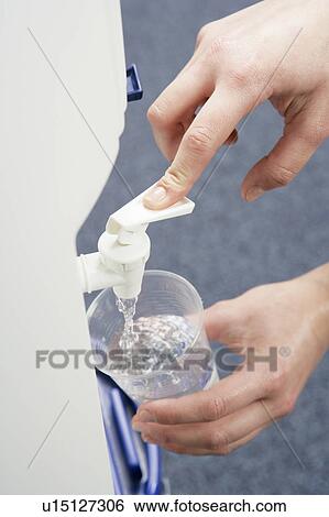 Stock Photograph - Woman filling cup at water cooler. Fotosearch