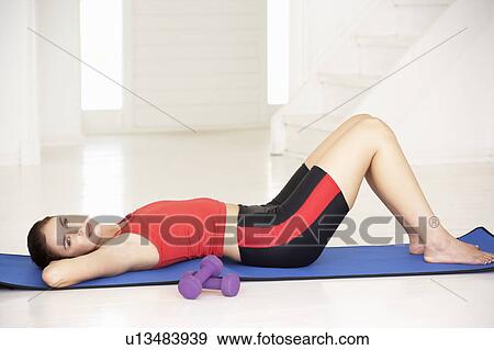 Stock Photo - Woman lying on exercise mat. Fotosearch