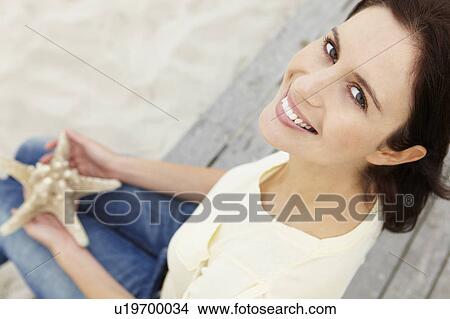 Woman sitting outdoors holding starfish View Large Photo Image Picture - Woman sitting outdoors holding starfish. Fotosearch