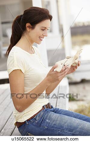 Stock Image - Woman sitting outdoors holding starfish. Fotosearch