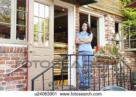 Stock Image - Woman standing outside bakery/cafÃ©. Fotosearch