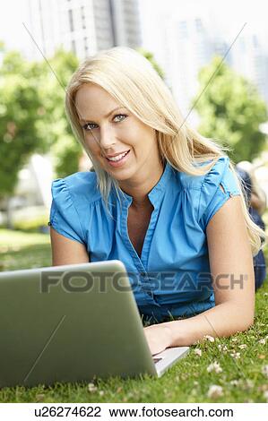 Stock Image - Woman using laptop in city park. Fotosearch