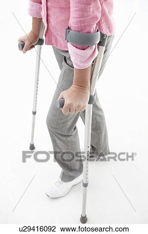 Stock Image - Woman walking with crutches. Fotosearch