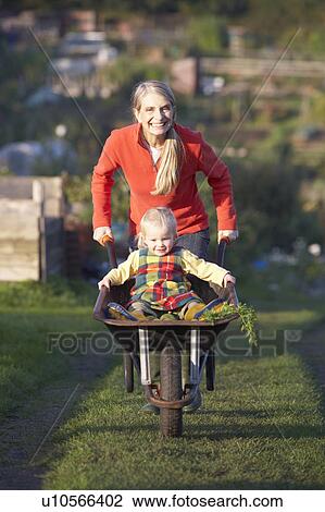 Stock Image - Woman working on allotment with child. Fotosearch