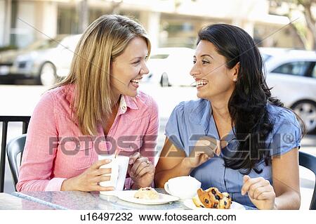 Stock Image - Women chatting over coffee and cakes. Fotosearch