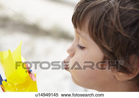 Stock Photography - Young boy blowing on windmill. Fotosearch