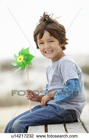 Stock Image - Young boy holding windmill into the wind. Fotosearch