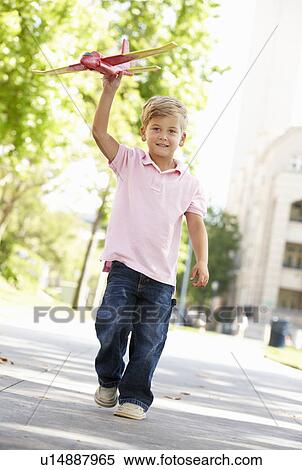 Young boy in street with toy aeroplane View Large Photo Image Stock Photography - Young boy in street with toy aeroplane. Fotosearch