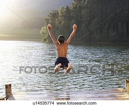 Picture - Young boy jumping into lake. Fotosearch