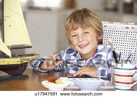 Stock Image - Young boy making model ship. Fotosearch