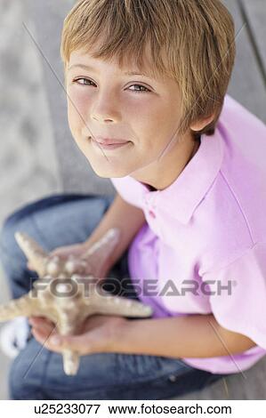 Stock Photo - Young boy outdoors holding starfish. Fotosearch