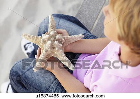 Stock Photography - Young boy outdoors holding starfish. Fotosearch