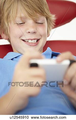 Stock Image - Young boy using cellphone. Fotosearch