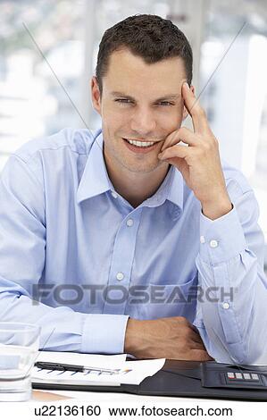Stock Image - Young businessman at desk. Fotosearch