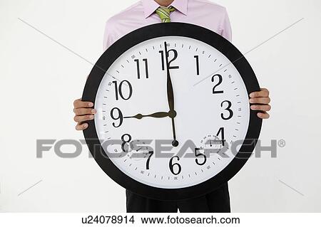 Picture - Young businessman with giant clock. Fotosearch