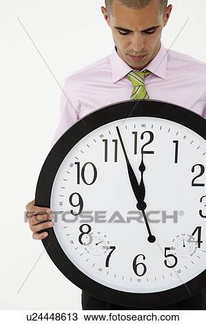 Stock Image - Young businessman with giant clock. Fotosearch