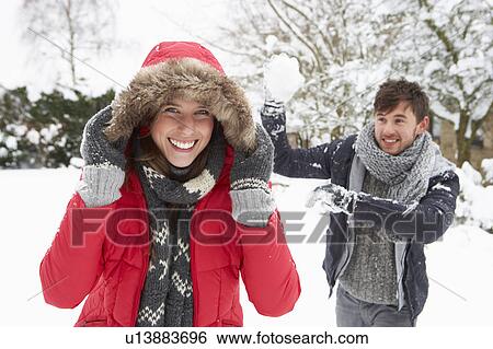 Stock Photograph - Young couple having snowball fight. Fotosearch
