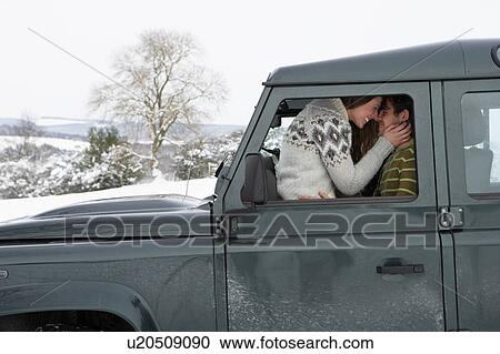 Stock Image - Young couple in car in snow. Fotosearch