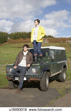Stock Photo - Young couple in countryside with SUV. Fotosearch