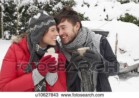 Stock Image - Young couple in snow with car. Fotosearch