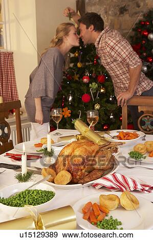 Young couple kissing under mistletoe at Christmas View Large Photo Image Stock Photo - Young couple kissing under mistletoe at Christmas. Fotosearch