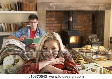 Stock Image - Young couple relaxing by fire. Fotosearch