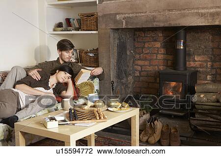 Stock Image - Young couple relaxing by fire. Fotosearch