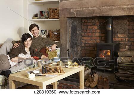 Stock Image - Young couple relaxing by fire. Fotosearch