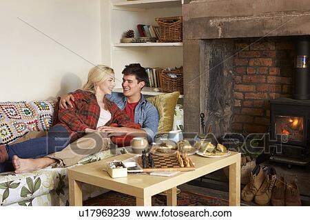 Stock Photo - Young couple relaxing by fire. Fotosearch