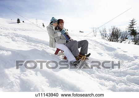 Stock Image - Young Couple Sledding. Fotosearch