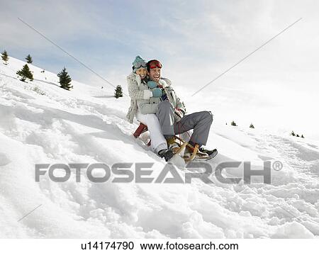 Stock Image - Young Couple Sledding. Fotosearch