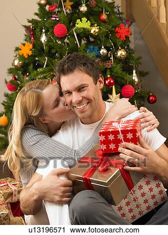 Young couple with gifts in front of Christmas tree View Large Photo Image Stock Image - Young couple with gifts in front of Christmas tree. Fotosearch