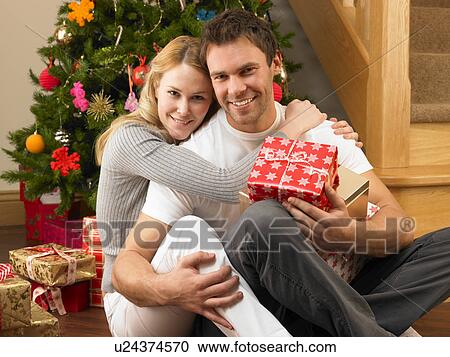Young couple with gifts in front of Christmas tree View Large Photo Image Stock Image - Young couple with gifts in front of Christmas tree. Fotosearch