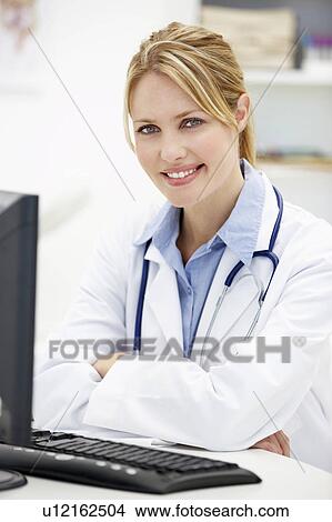 Picture - Young doctor at desk. Fotosearch