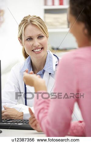 Stock Photograph - Young doctor with female patient. Fotosearch