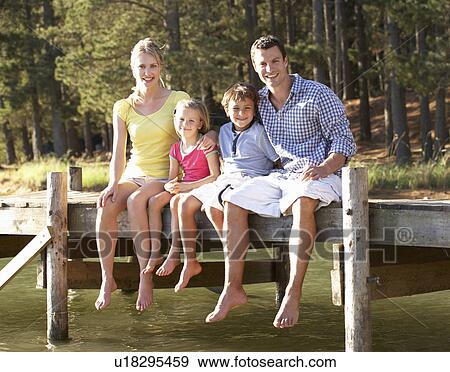 Stock Photo - Young family sitting by lake. Fotosearch