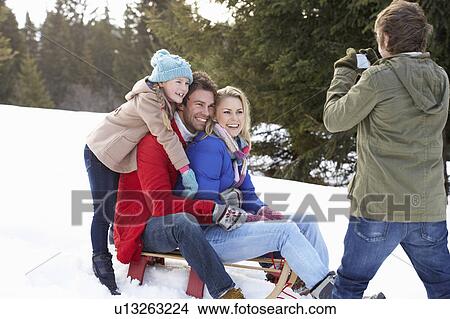Picture - Young Family Sitting On A Sled In The Snow. Fotosearch