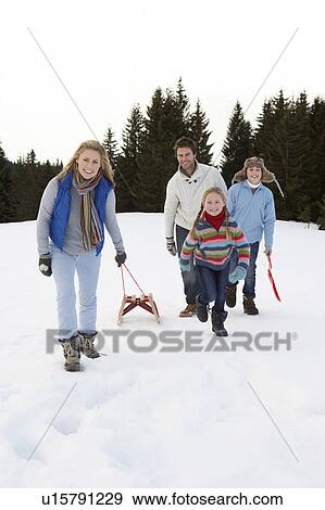 Stock Photo - Young Family Walking Through Snow With Sled. Fotosearch