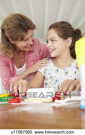 Stock Image - Young girl baking with grandmother. Fotosearch