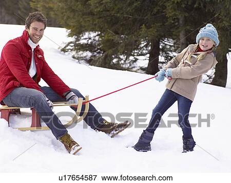 Stock Photo - Young Girl Pulling Father Through Snow On Sled. Fotosearch