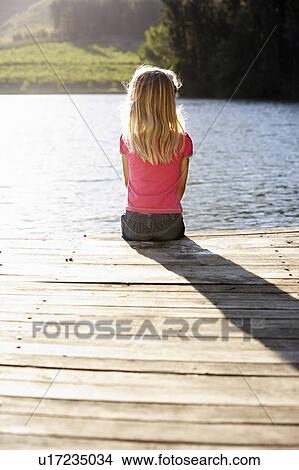 Picture - Young girl sitting by lake. Fotosearch