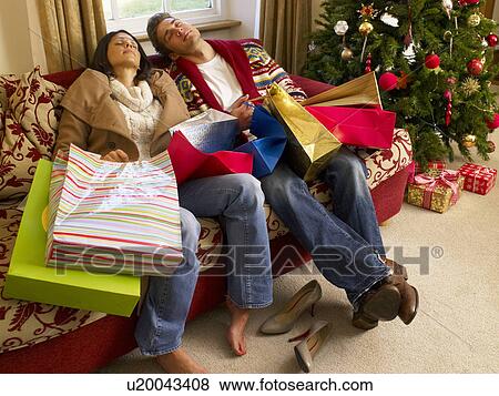Stock Photo - Young Hispanic couple resting after Christmas shopping. Fotosearch