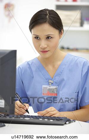 Stock Image - Young hospital doctor at desk. Fotosearch