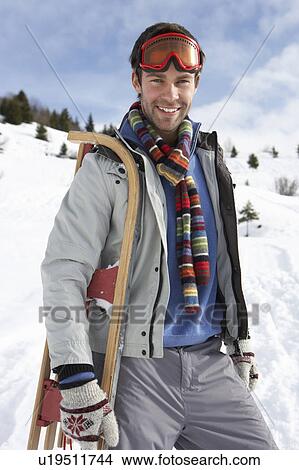 Picture - Young Man Carrying Sled In Alpine Landscape. Fotosearch