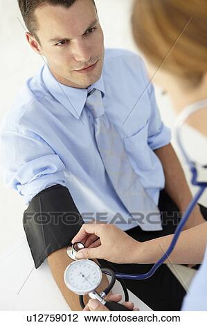 Stock Image - Young man having blood pressure taken. Fotosearch