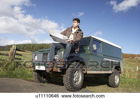 Stock Photograph - Young man in countryside with SUV. Fotosearch